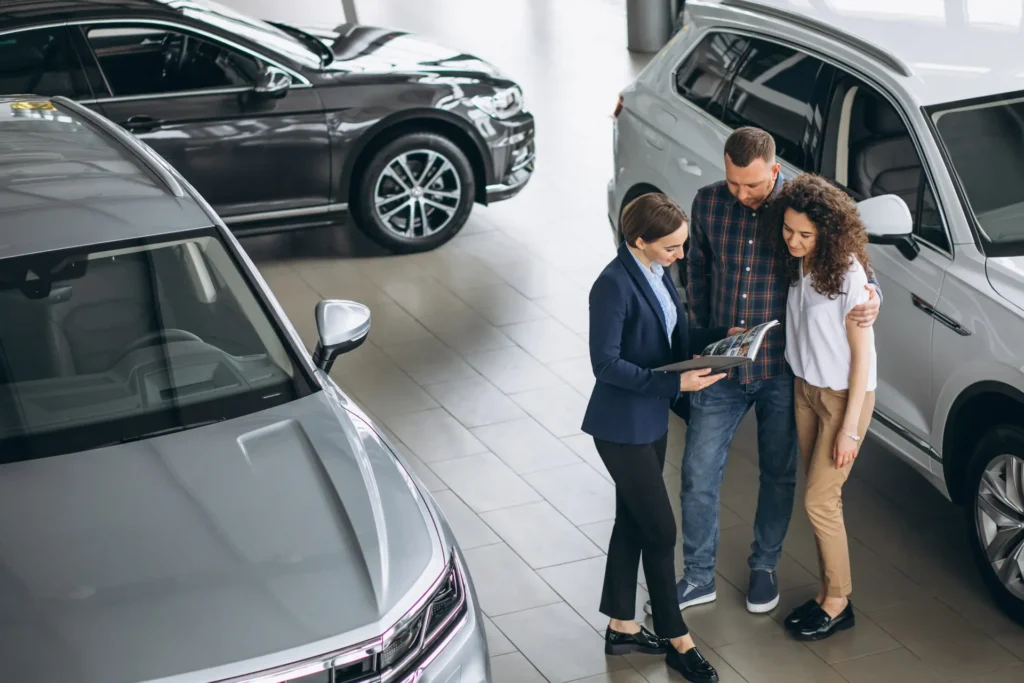 Exhibición de autos seminuevos en un concesionario con clientes observando vehículos