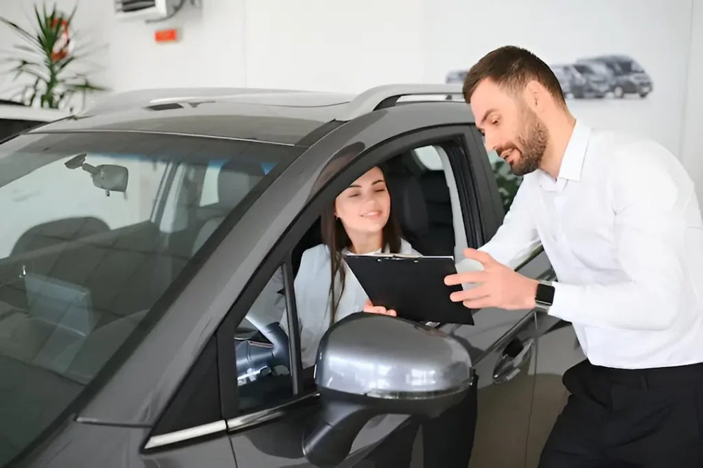 Asesor de concesionario explicando la garantía de un auto seminuevo a un cliente
